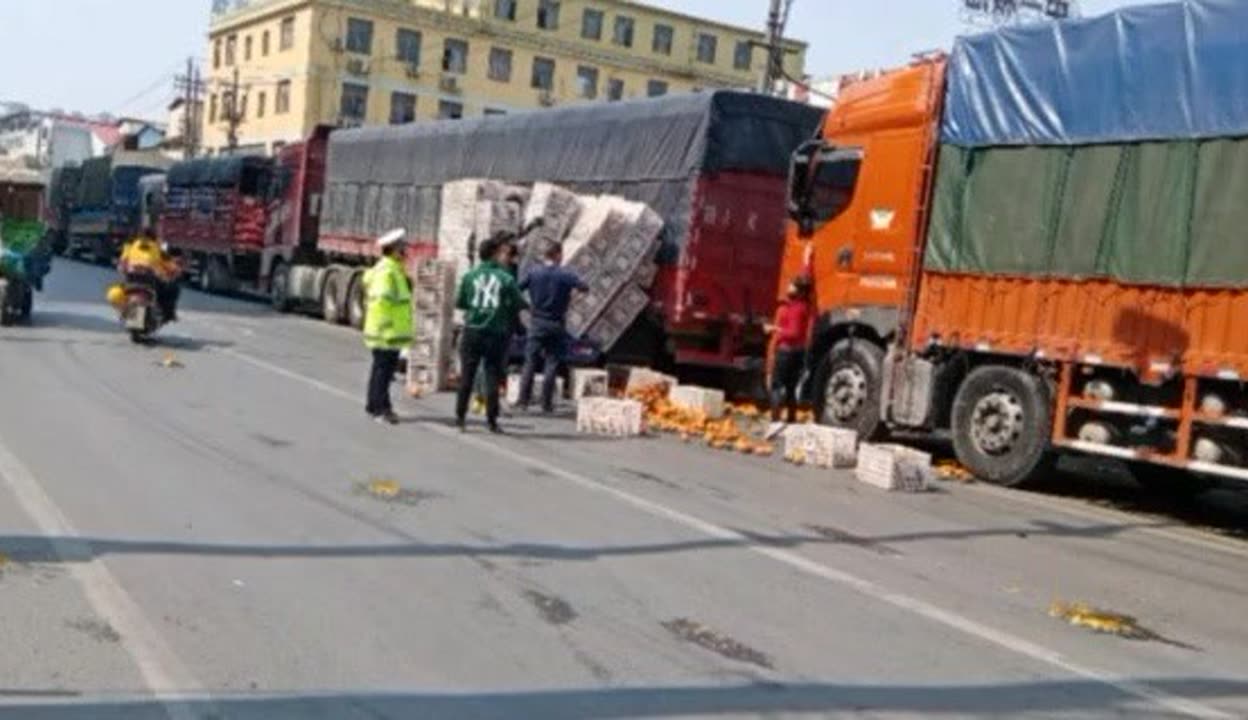 南昌深圳农产品批发市场。2号门这条路上天天堵车。你看货车进场,都排起了长龙。快看个货车傍边一车桔子都倒掉了。